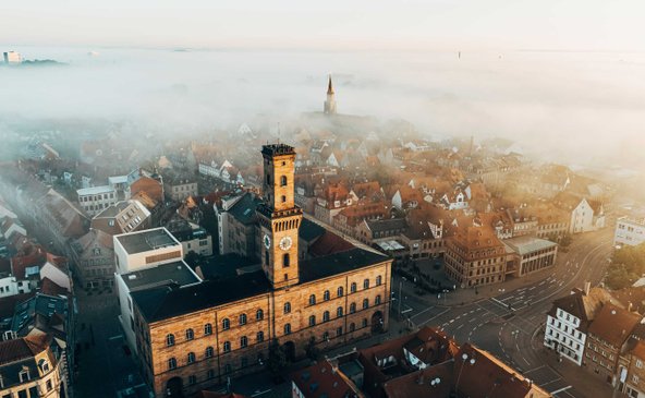 Luftaufnahme des Rathauses Fürth mit Altstadt im Hintergrund und leichtem Nebel über den Gebäuden