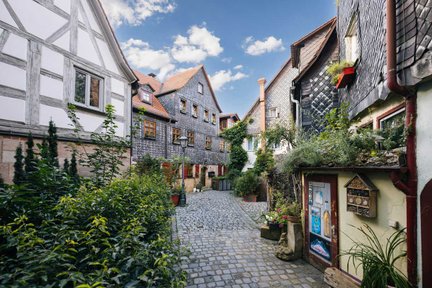 Pfarrgasse in Fürth mit Schieferhaus, Fachwerk und vielen Pflanzen im Sommer.