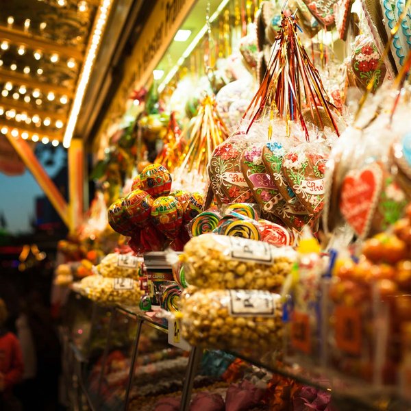Hell beleuchteter Süßigkeitenstand mit gebrannten Nüssen, Popcorn, Lollis und Lebkuchenherzen.