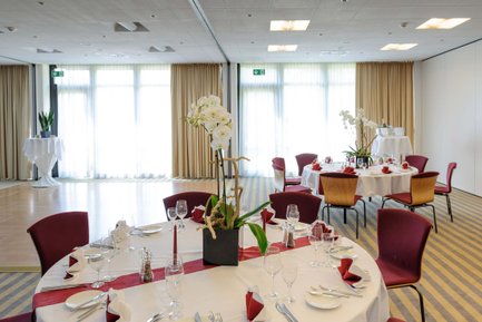 Runder Tagungsraum im Mercure Hotel Nürnberg West mit festlich geschmückten Tischen und Blumendeko