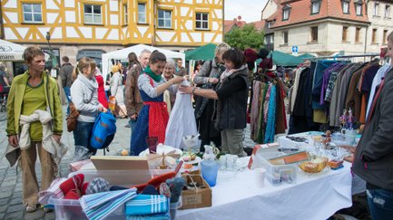 Besucherinnen betrachten Kleidung an einem Flohmarktstand auf dem Graffelmarkt