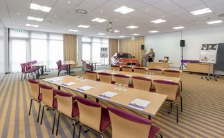 Heller Tagungsraum im Mercure Hotel Nürnberg West mit Reihenbestuhlung, Tischen und Präsentation