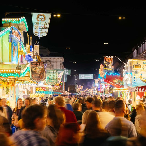 Nächtliche Michaelis-Kirchweih mit Besuchern, die durch bunt beleuchtete Budenstraße schlendern