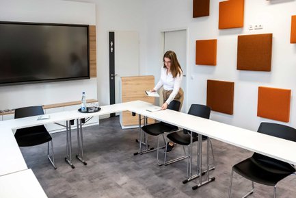 Mitarbeiterin verteilt Schreibblöcke auf Tischen im Tagungsraum der Fürther Tourist-Information