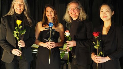Vier Künstler:innen in eleganter Abendkleidung halten farbige Rosen beim Komponistinnensommer.