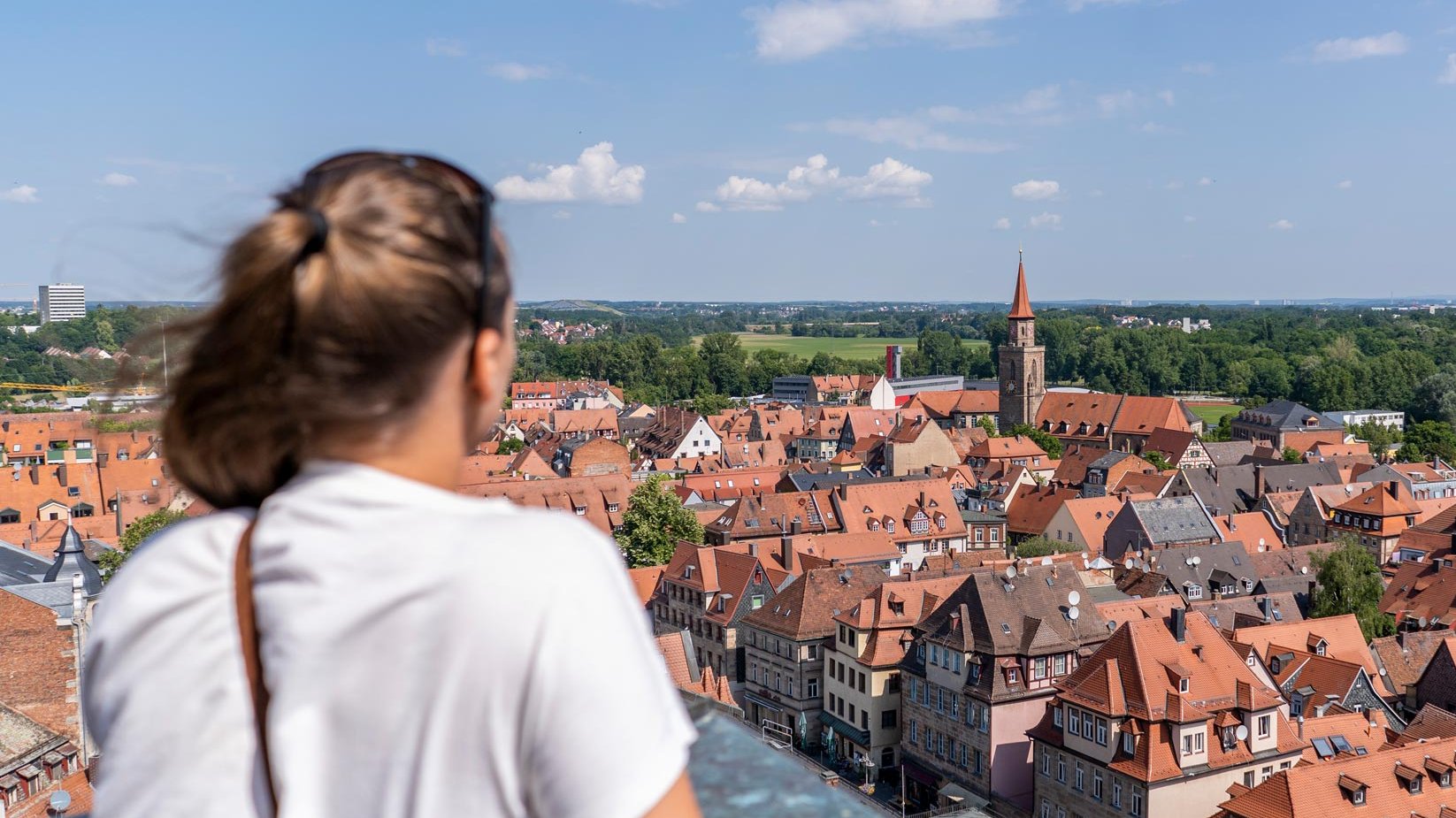 Junge Frau auf dem Rathausturm in Fürth schaut auf die Altstadt mit historischen Gebäuden.