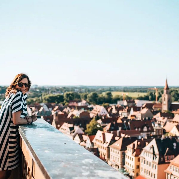 Eine Bloggerin lächelt auf dem Fürther Rathausturm, im Hintergrund die Altstadt der Stadt Fürth.