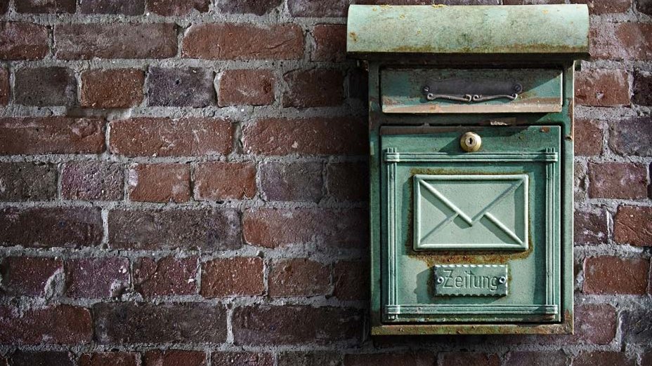 Ein nostalgischer Briefkasten im Retrodesign hängt an einer roten Backsteinwand