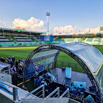 Bühne neben dem Spielfeld im Sportpark Ronhof, im Hintergrund Gegengerade und Nordtribüne sichtbar