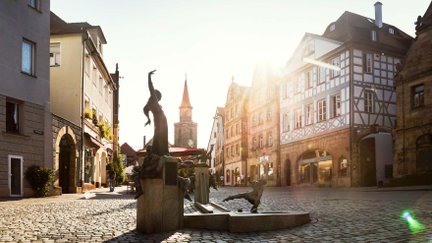 Gauklerbrunnen auf dem Grünen Markt in Fürths Altstadt, umgeben von historischen Häusern und St.-Michael-Kirchturm.