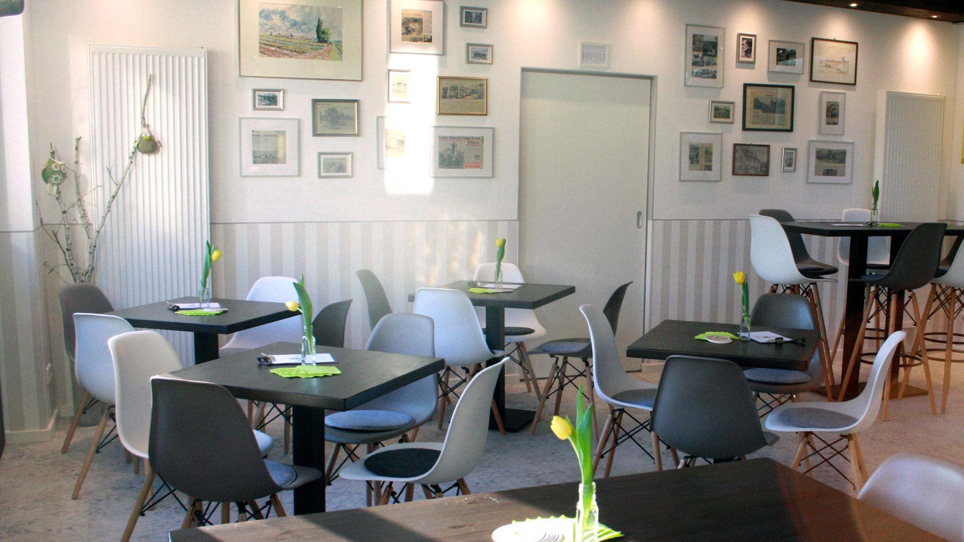Gemütlicher Innenraum von Frankies Hofladen mit Tischen, gelben Tulpen und dekorierter Bilderwand.