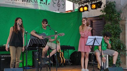Zwei Sängerinnen, Gitarrist und Cajón-Spieler performen live auf der Bühne der Grünen Nacht.