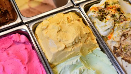 Verschiedene bunten Eissorten in Edelstahlbehältern einer Eisdiele in der Nahaufnahme.