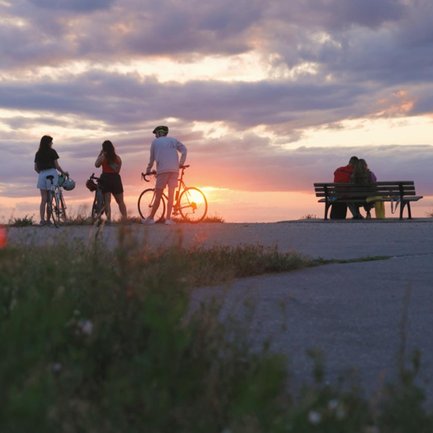 Eine kleine Fahrradgruppe auf dem Fürther Solarberg genießt den farbenprächtigen Sonnenuntergang