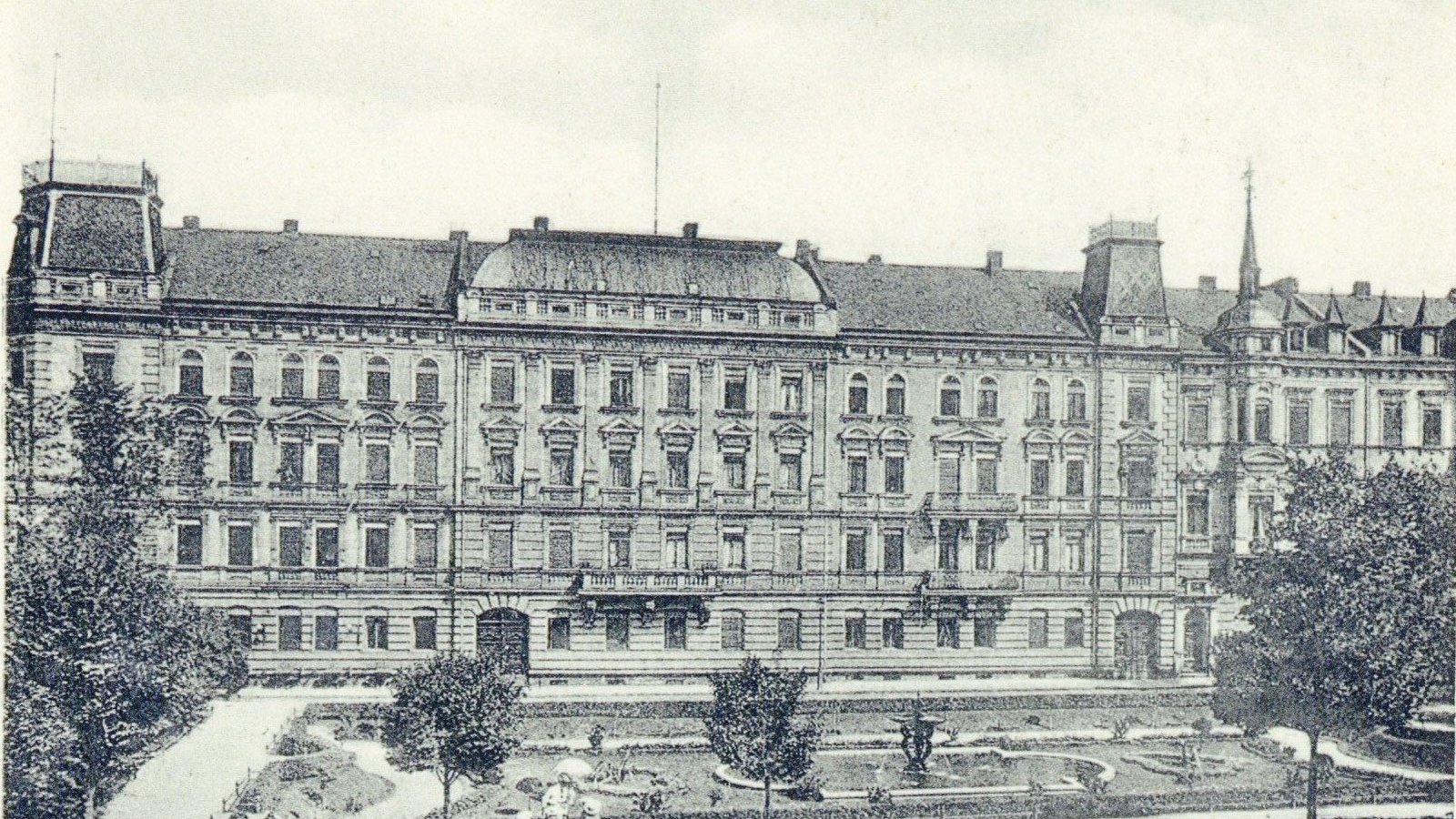 [Translate to English:] Historische Sandsteinhäuser an der Fürther Hornschuchpromenade mit der begrünten Willy-Brandt-Anlage und einem Springbrunnen.