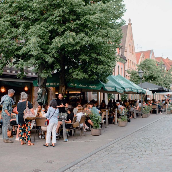 Viele Menschen sitzen in der Gustavstraße und unterhalten sich an Tischen