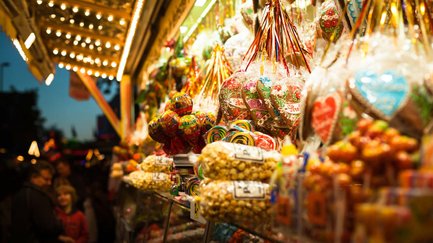 Hell beleuchteter Süßigkeitenstand mit gebrannten Nüssen, Popcorn, Lollis und Lebkuchenherzen.