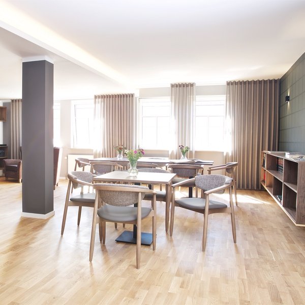 Heller, gemütlicher Raum in der Rosengarten Residenz mit Parkettboden, Tischen und Stühlen