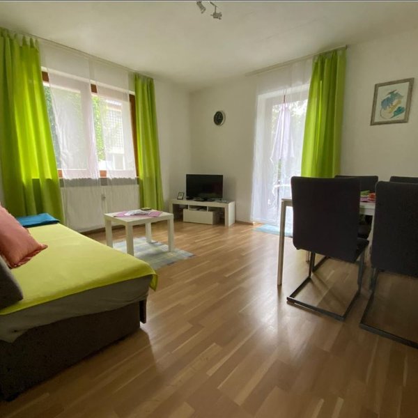 Wohnzimmer des Apartments Falke in Fürth mit kleiner Couch, Esstisch und grünen Akzenten