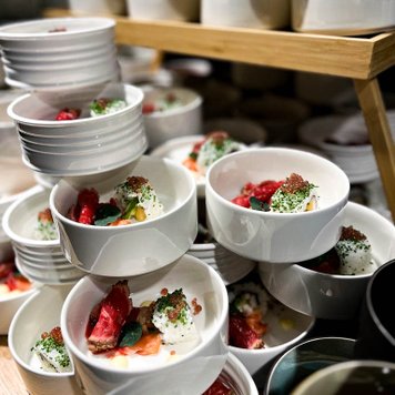 Mehrere weiße Schalen mit kunstvoll angerichteten Vorspeisen, ideal für Events oder Catering.