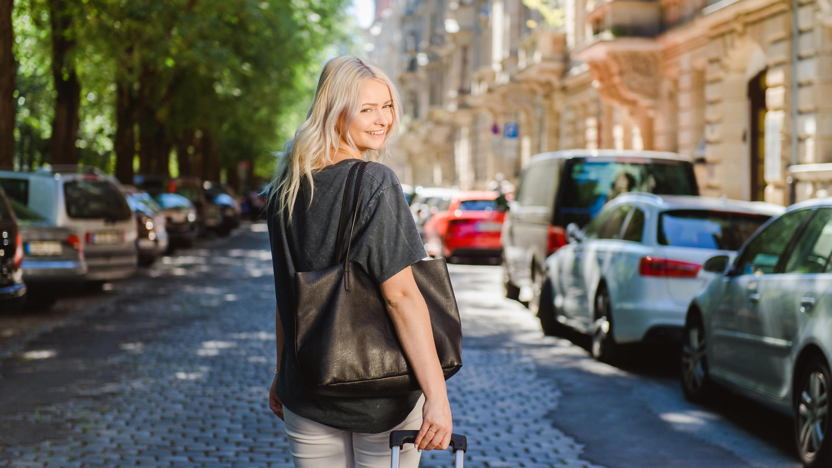 Junge Touristin mit Koffer läuft durch die Hornschuchpromenade in Fürth, umgeben von historischen Sandsteinbauten.