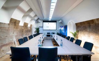 Kellergewölbe in Castros Bar mit rechteckig aufgestellten Tischen, Leinwand, Flipchart und Sandsteinwand