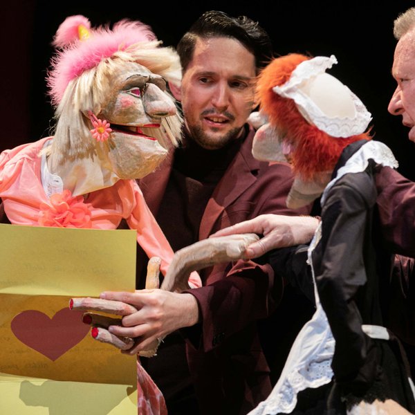 Zwei Puppen beim internationalen Figuren-Theaterfestival, eine liest einen Liebesbrief vor, Puppenspieler sichtbar