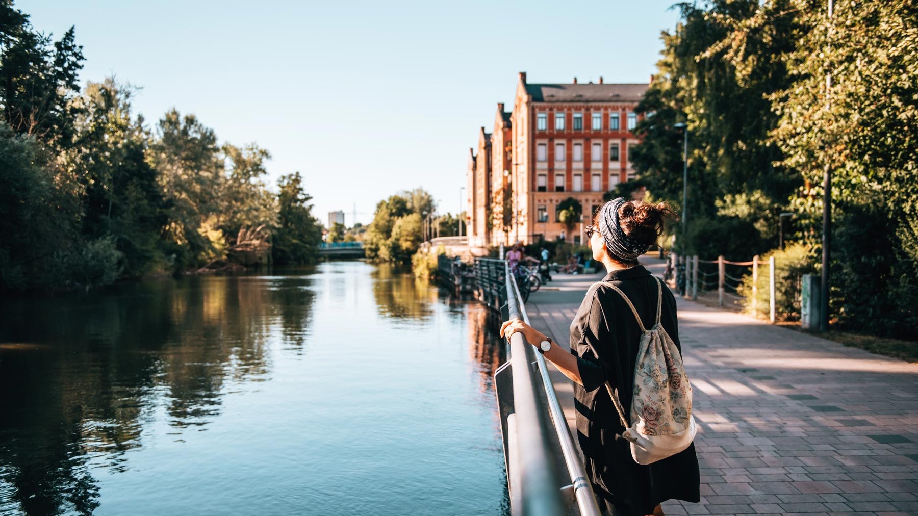 Frau steht an der Uferpromenade der Rednitz in Fürth, genießt die Sonne und schöne Atmosphäre.
