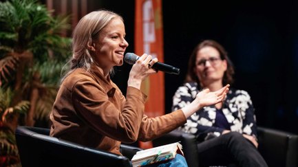 Julia Engelmann sitzt auf einem Sessel, spricht ins Mikrofon und liest aus einem Buch vor.