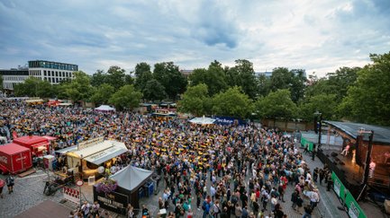 Besucher feiern auf der Fürther Freiheit beim Festival und genießen Musik, Getränke und Essen.