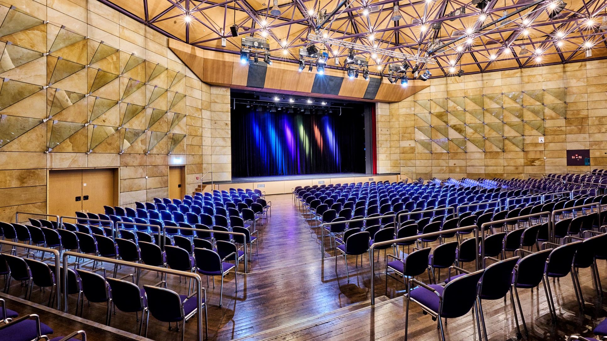 Innenansicht der Stadthalle mit aufgebauten Stuhlreihen und beleuchteter Bühne für kommende Veranstaltung
