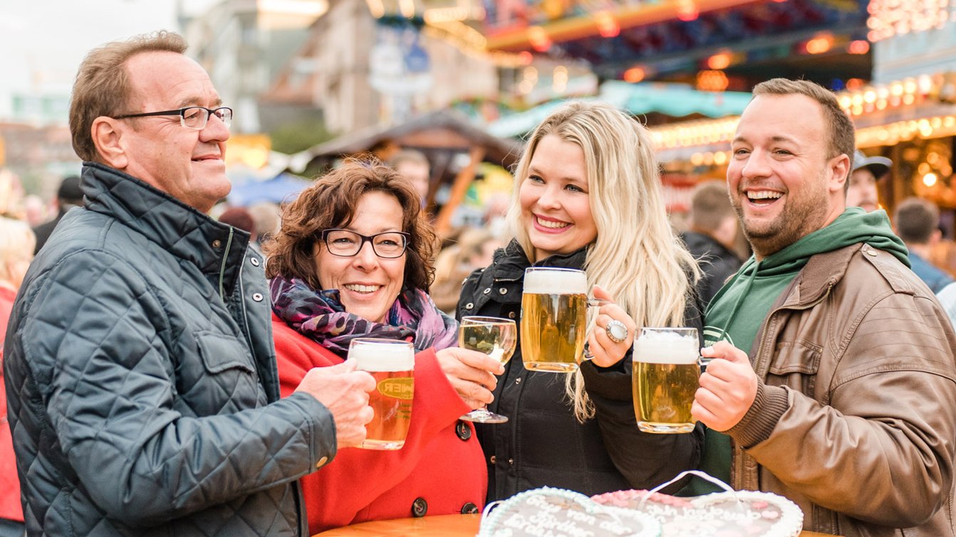 Pärchen genießen die Michalis-Kirchweih mit Bier und Wein, umgeben von Fahrgeschäften und Buden.