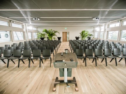 Moderner, lichtdurchfluteter Konferenzraum im iba Forum Fürth mit Holzboden, Stuhlreihen und Pflanzen