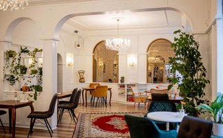 Innenraum des Café Zanetta mit Kronleuchtern, Teppich und Sesseln, ideal für Feierlichkeiten und Mietungen