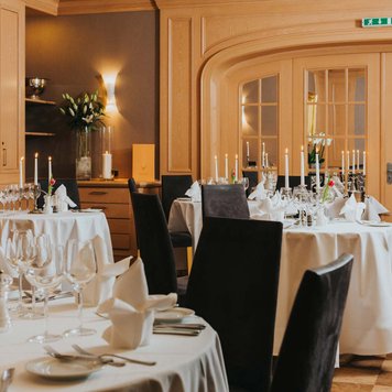 Runde, festlich gedeckte Tische im Hotel Forsthaus Fürth mit Kerzen und kariertem Boden