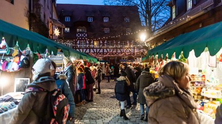 Besucher schlendern über die warm beleuchteten Altstadtweihnacht mit ihren Holzbuden.