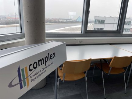 Stühle und Tische im complex Fürth an Fensterfront mit Blick auf die Pyramide Fürth