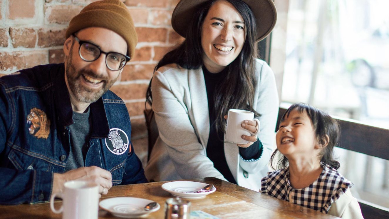Junge Familie genießt Kaffee in der Kaffeebohne in Fürth, mit der Bachsteinfassade im Hintergrund.