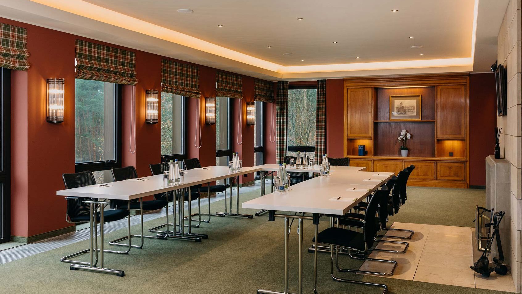 Gemütlicher Tagungsraum mit U-Form-Bestuhlung, warmen Farben, Kamin und Blick in den Wald