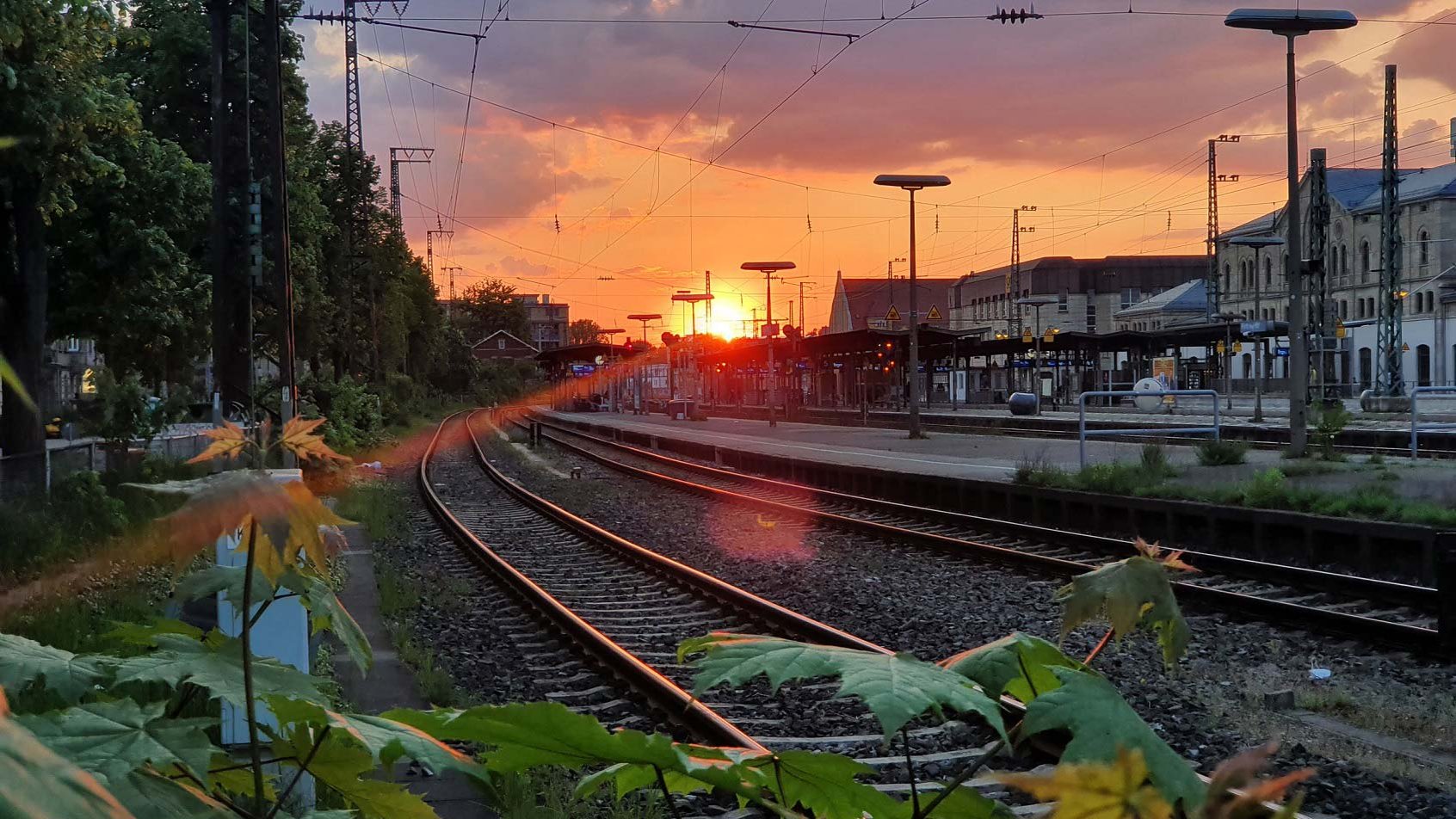 Blick auf die Gleise und den Fürther Hauptbahnhof bei Sonnenuntergang mit orangefarbenem Himmel