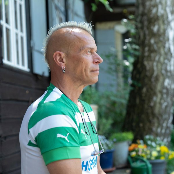 Udo Schick sitzt nachdenklich im grünen Garten des Kulturorts Badstraße in entspannter Atmosphäre.