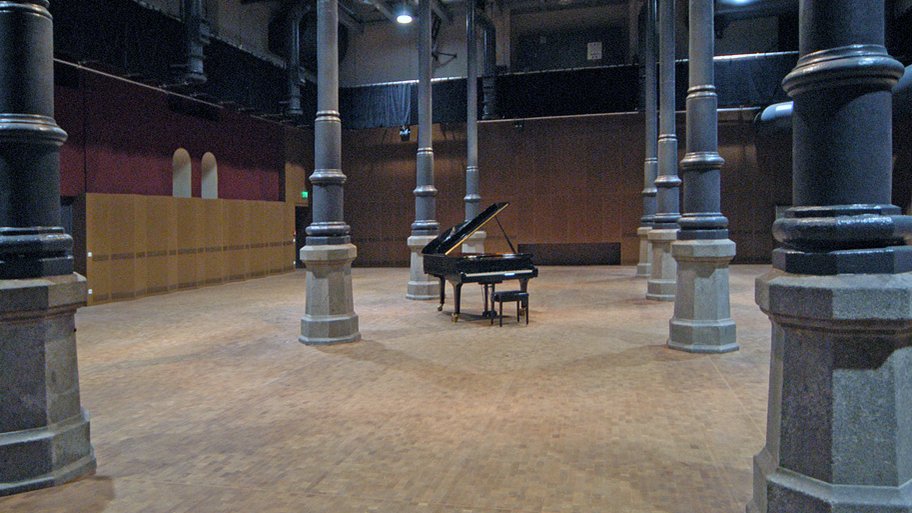 Ein schwarzer Konzertflügel steht im Kulturforum zwischen hohen, eleganten Säulen.