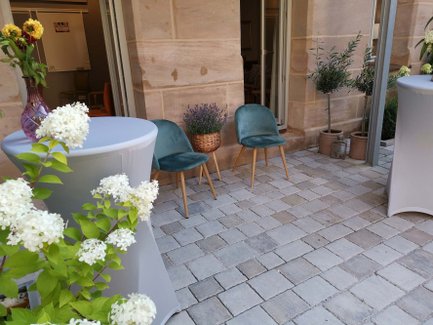 Außenbereich der Location Wohnzimmer Fürth mit Stehtischen, Stühlen, Pflanzen und Sandsteinfassade