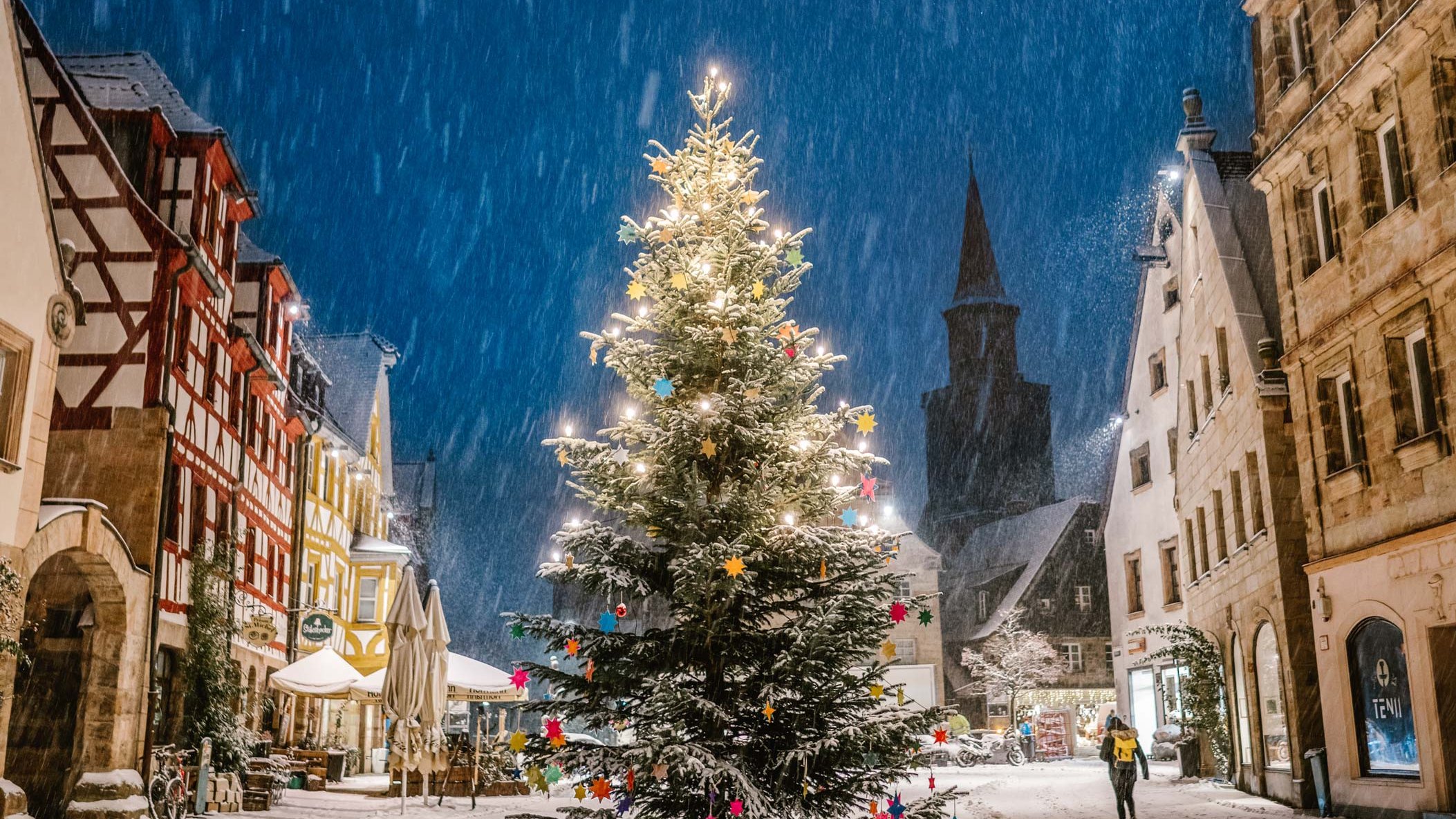 Geschmückter Weihnachtsbaum am Grünen Markt in Fürth, umgeben von Altstadthäusern im nächtlichen Schneefall.