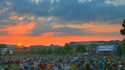Publikum auf Picknickdecken lauscht beim Südstadt Klassik Open Air dem Orchester im warmen Abendlicht.