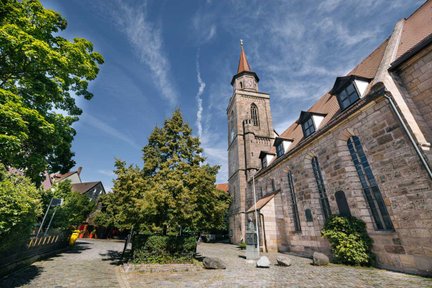 Kirche St. Michael, ältestes noch stehende Gebäude in Fürth, mit Kirchvorplatz unter blauem Himmel.