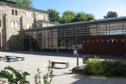 Innenhof des Kulturforum Fürth mit Blick auf Glasfassade, Eingangsbereich, Sonnenschein und blauem Himmel