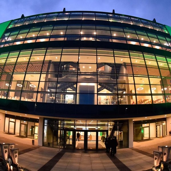 Modernes Außengebäude der Haupttribüne im Sportpark Ronhof | Thomas Sommer, grün beleuchtet mit großer Glasfassade