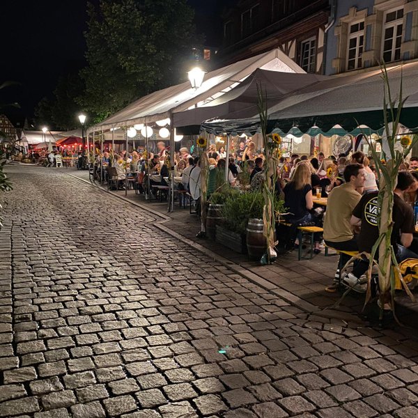Besucher sitzen vor den Lokalen der Gustavstraße und genießen beim Weinfest gemeinsam den Abend bei einem Getränk.