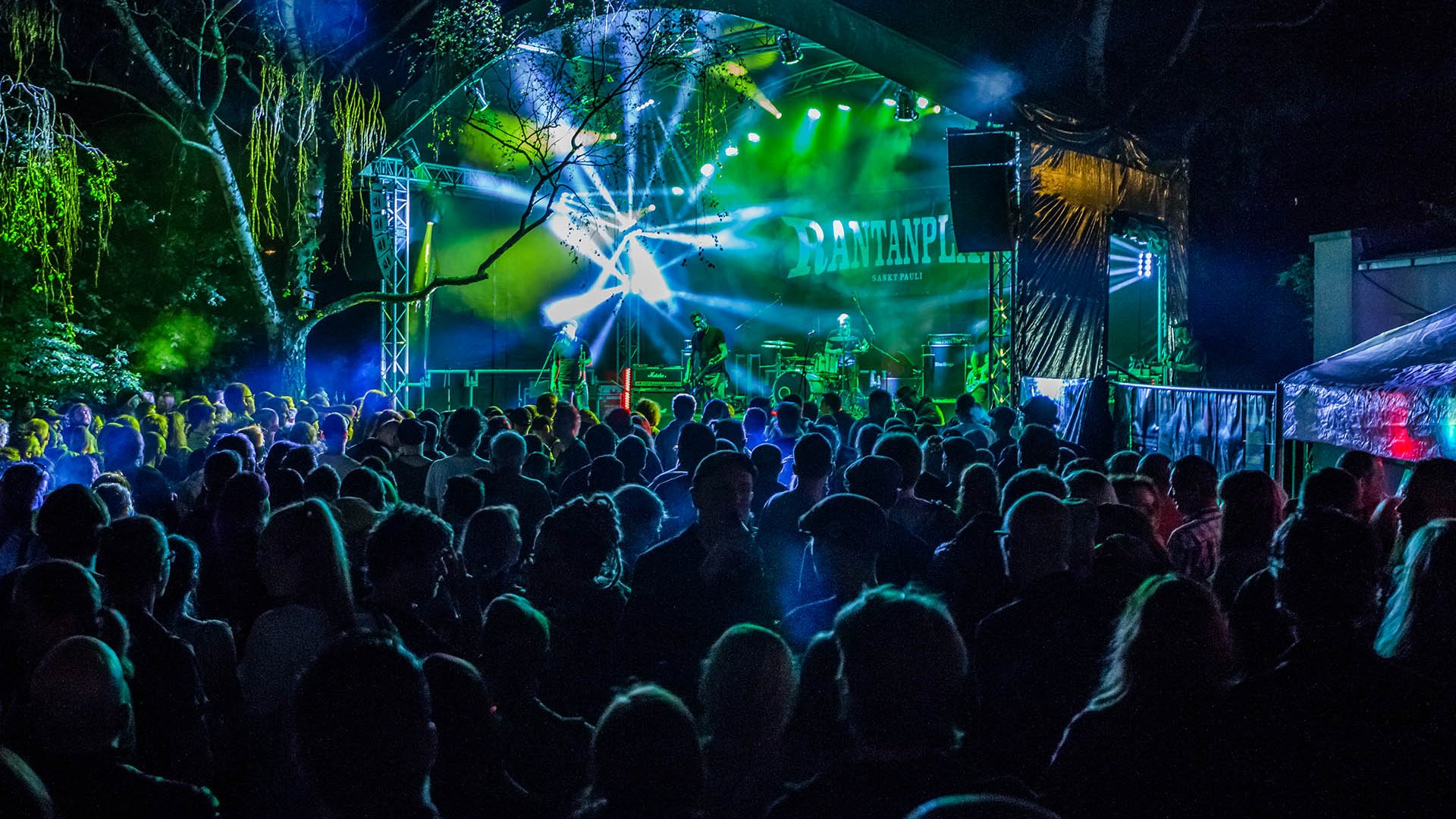 Live-Band spielt auf Festivalbühne, Besucher tanzen und genießen Musik bei bunten Lichteffekten.